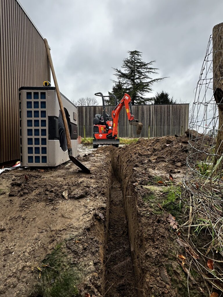 EYSKENS Machinery Kubota U10-5 graaft smalle nutssleuf tussen warmtepomp en houten omheining
